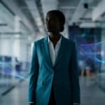 Une femme d'affaires noire dans un bureau moderne entourée d'effets visuels de données numériques ondulantes.