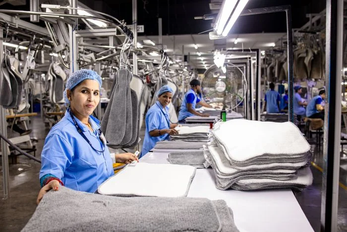 Personnel dans un atelier de blanchisserie avec des piles de linge plié
